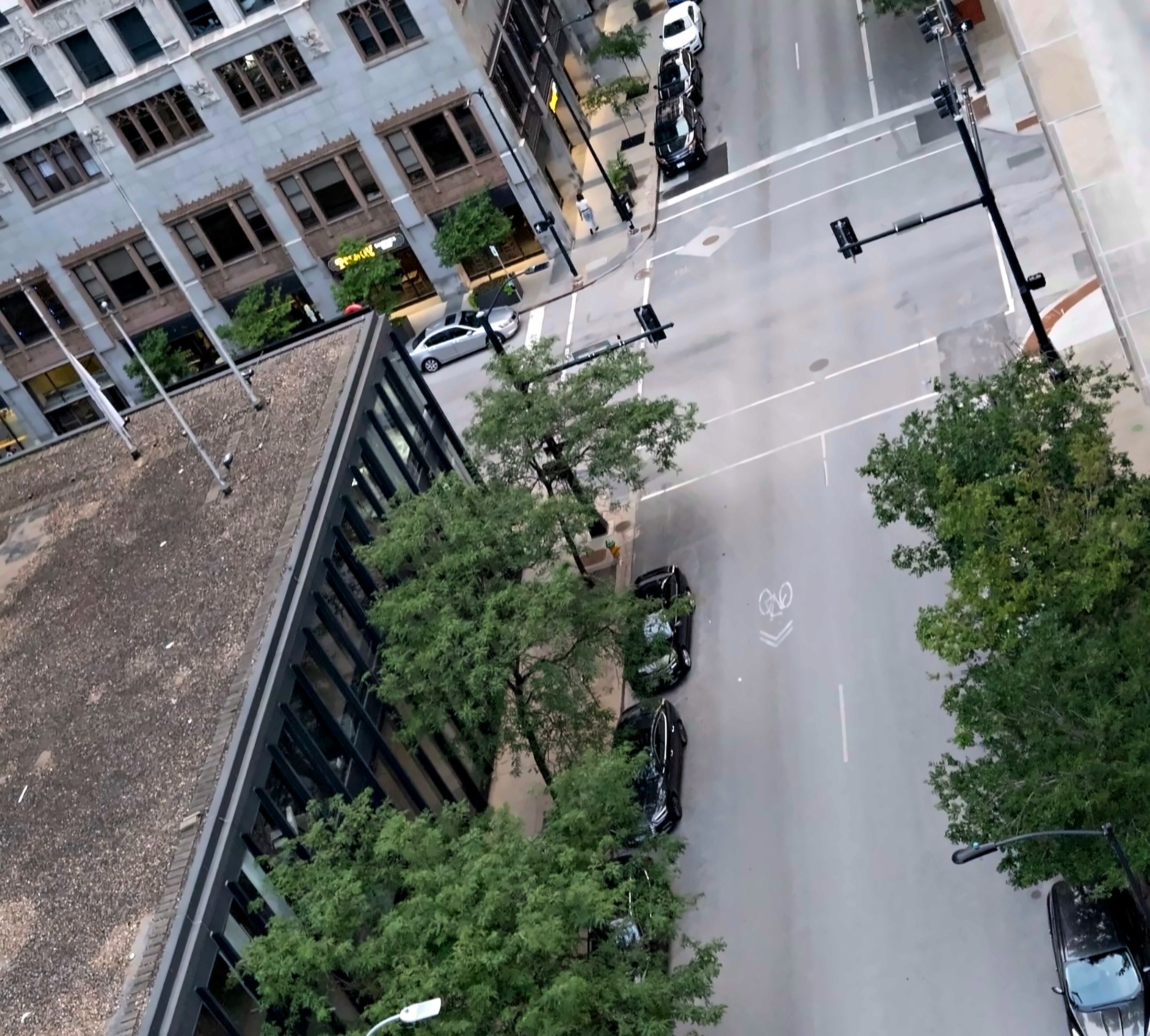 Overhead view of a downtown intersection lined with trees and parked cars